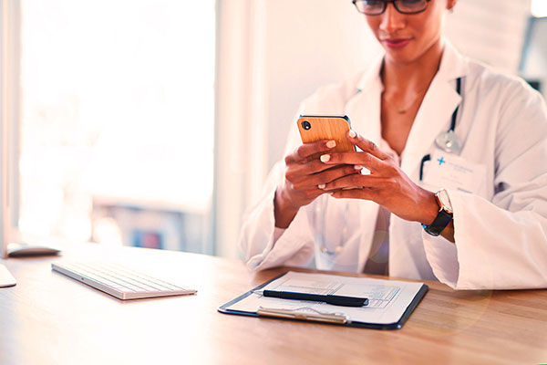 A female doctor holding a smartphone sitting at a table